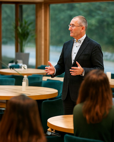 service5 Thomas Pollmann im Gespräch mit Teilnehmenden während eines Seminars in einem lichtdurchfluteten Tagungsraum